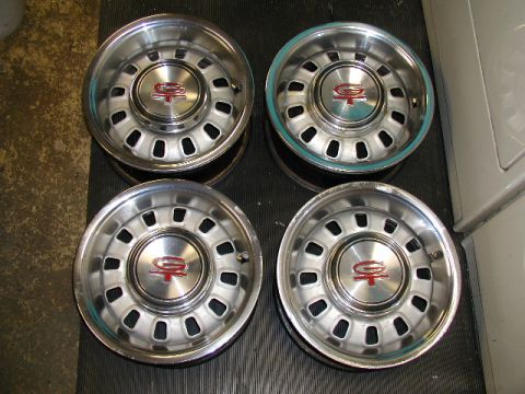 1967 Ford Ranchero - Four chrome wheel covers with red center caps are displayed, likely for sale as used parts.