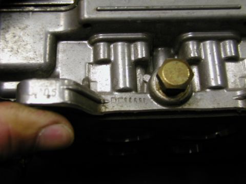 1967 Ford Ranchero - A close-up view of a metal carburetor component, showing stamped markings and a brass bolt.