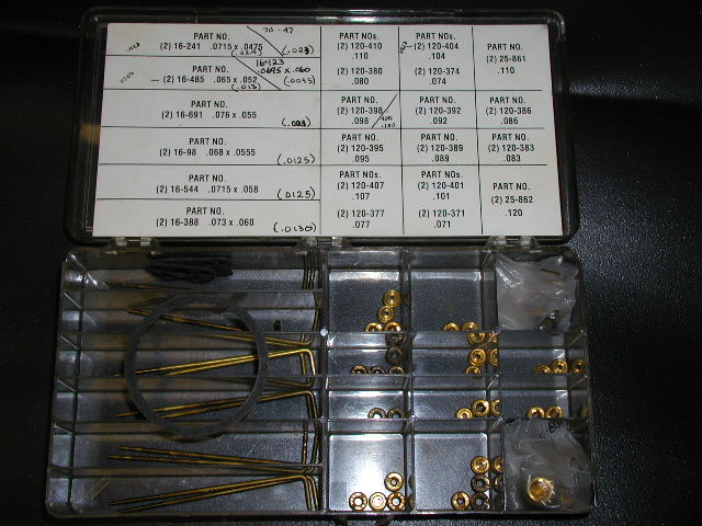 Carburetor tuning kit case with brass metering rods, jets, and a part-number chart in the lid