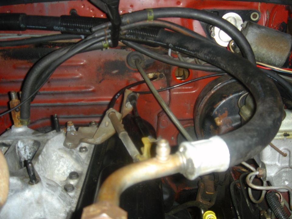 1986 Ford Mustang engine bay with red firewall, hoses, and metal components