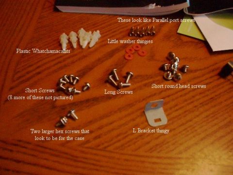 1993 Ford Probe - A collection of assorted screws, plastic fasteners, and a metal bracket are displayed on a wooden table, with labels identifying each item.