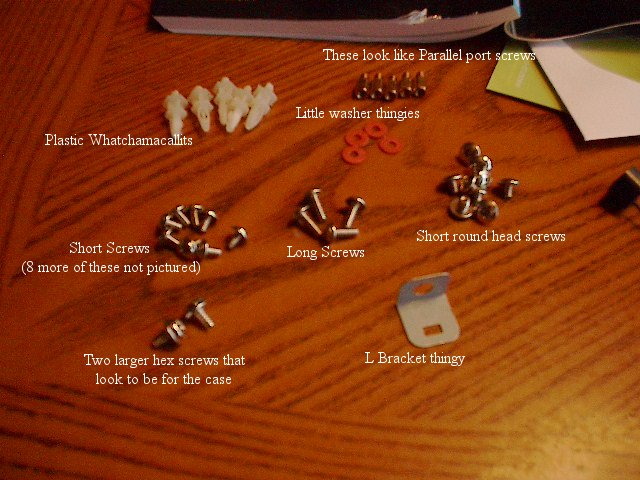 Various screws, plastic parts, and an L-bracket laid out on a wooden surface