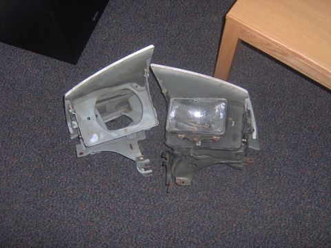 1994 Ford Probe - Two car headlights are shown on a carpeted surface, with one unit a clear glass lens.