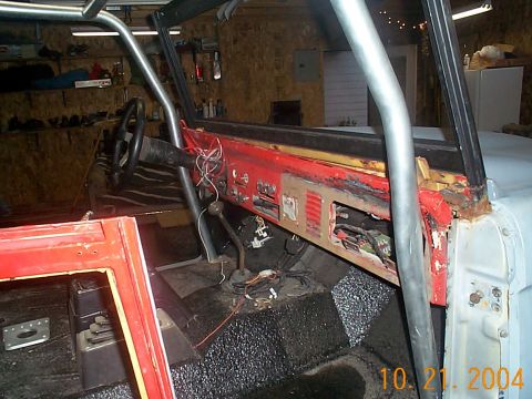 1974 Ford Bronco - The interior of a 1974 Ford Bronco shows a red dashboard and a roll cage, indicating it is undergoing modifications.