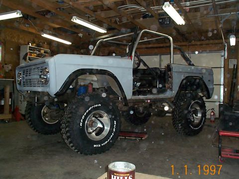 1974 Ford Bronco - A 1974 Ford Bronco is undergoing modifications in a workshop, showing its lifted suspension and roll cage.