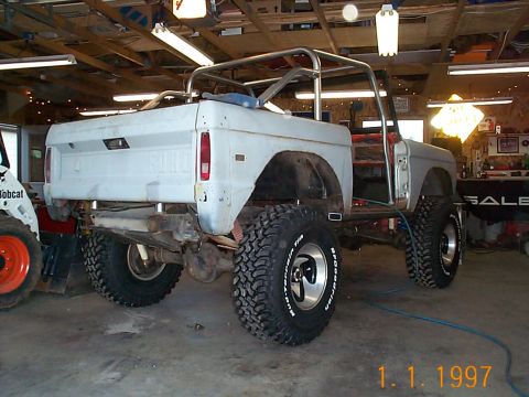 1974 Ford Bronco - This 1974 Ford Bronco is shown in a garage with a roll cage and oversized tires, suggesting it is undergoing modifications.
