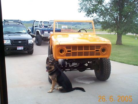 1974 Ford Bronco - An orange Ford Bronco sits in front of a black SUV and a blue Bronco.