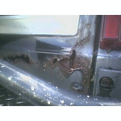 1981 Ford Bronco - Close-up of significant rust damage on the rear corner of a vehicle.