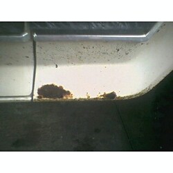 1981 Ford Bronco - Close-up of rust damage on the lower body panel of a vehicle.