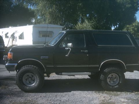1987 Ford Bronco - Side profile of a black 1987 Ford Bronco, showing its classic SUV body style and lifted stance.