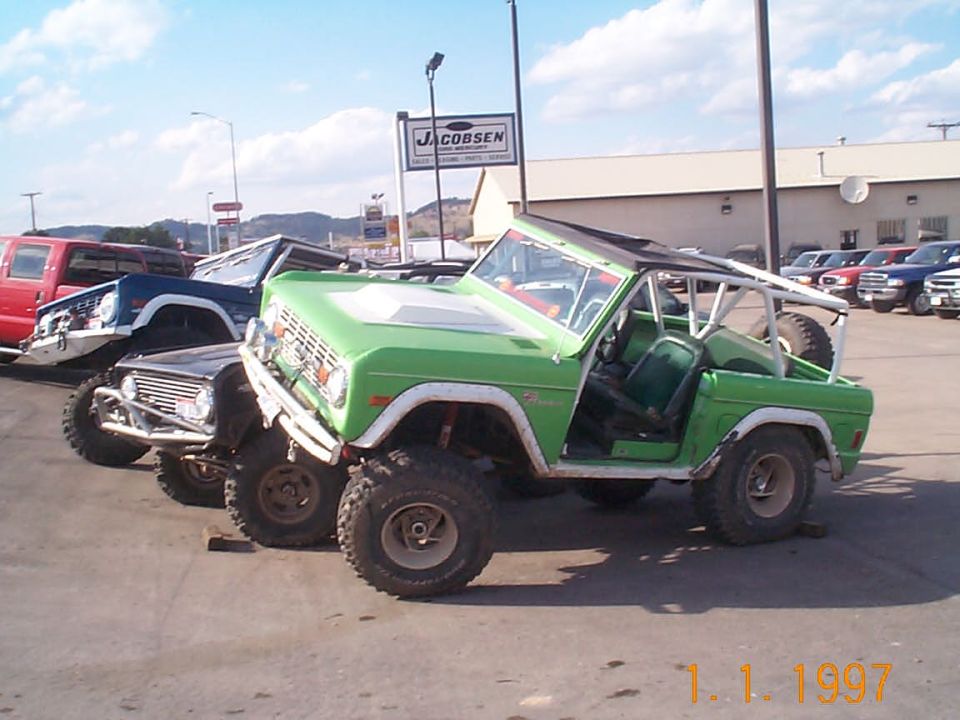 Green Ford Bronco and other SUVs parked outside a dealership