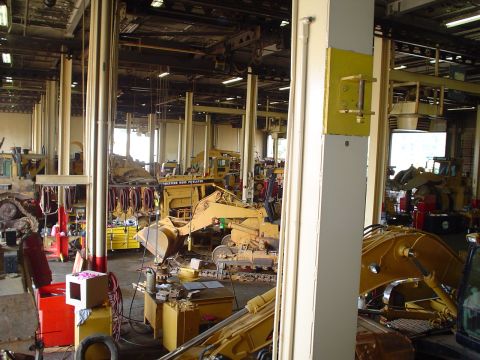 1966 International School Bus - A busy repair bay filled with heavy machinery, tools, and workbenches.
