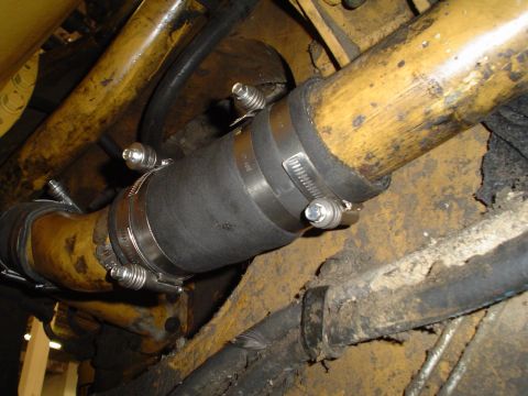 1966 International School Bus - A close-up view of a rubber hose secured with metal clamps to yellow pipes, likely part of an engine system.