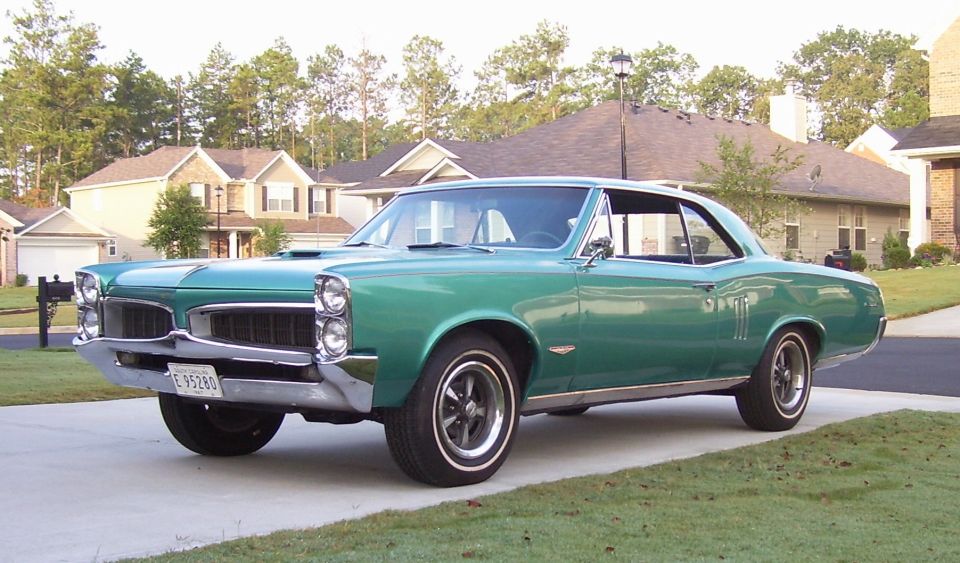 Green 1967 Pontiac GTO parked in driveway, front quarter view. License plate E 95280