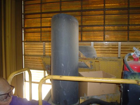 1966 International School Bus - Interior view of a yellow vehicle, showing a large exhaust stack and a red fire extinguisher mounted to the side.