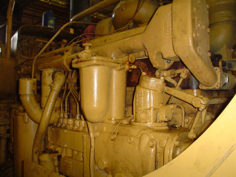 Close-up of a yellow engine, likely from heavy equipment. Shows fuel injectors and piping