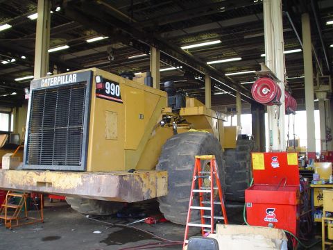 1966 International School Bus - Caterpillar 990 wheel loader undergoing maintenance in a workshop environment.