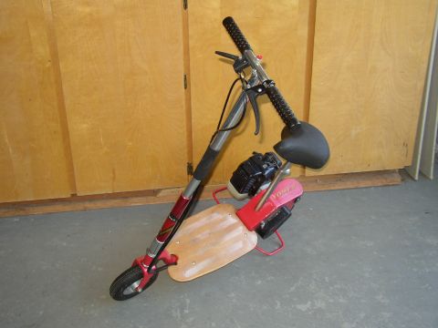 1987 Volkswagen Golf - Motorized scooter with a wooden deck and black seat parked indoors.