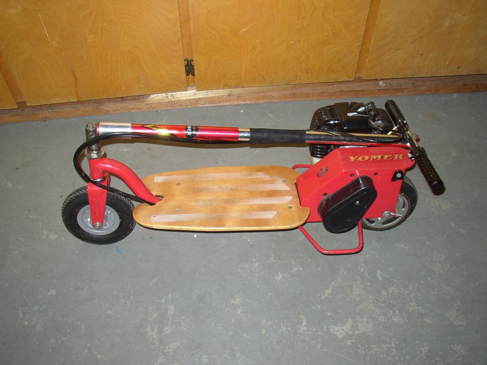 Red motorized scooter with wooden deck and YOMER branding