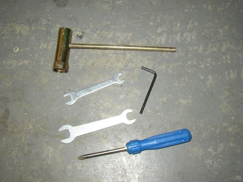 1987 Volkswagen Golf - A collection of tools, including a socket wrench, open-end wrenches, an Allen wrench, and a screwdriver, are laid out on a concrete surface.
