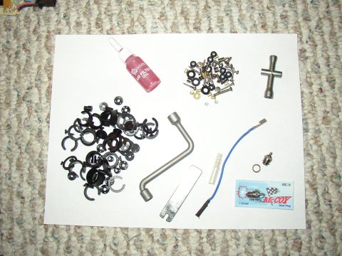 1987 Volkswagen Golf - Various automotive parts and tools are laid out on a white sheet of paper on a carpeted surface.