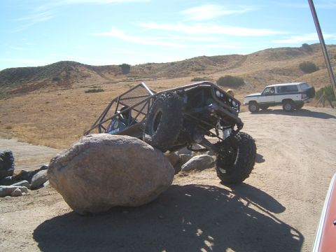1988 Ford Bronco - A heavily modified 1988 Ford Bronco is navigating a rocky obstacle course, with another white Bronco visible in the distance.