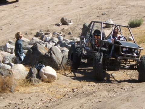 1988 Ford Bronco - An off-road buggy with a prominent roll cage navigates a rocky, dusty terrain.