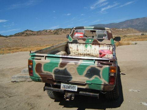 1988 Ford Bronco - This Toyota pickup truck is painted in a camouflage pattern and has a red gas can in the truck bed.