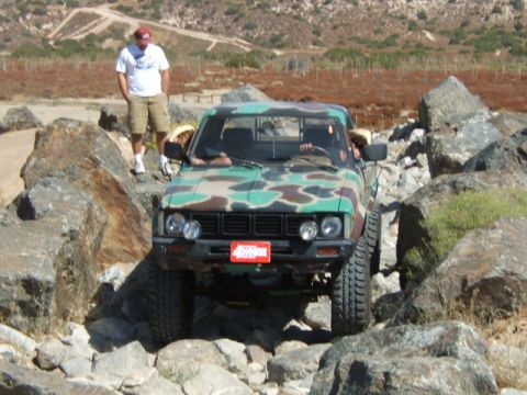 1988 Ford Bronco - A camouflage pickup truck is shown navigating a challenging rocky obstacle course.