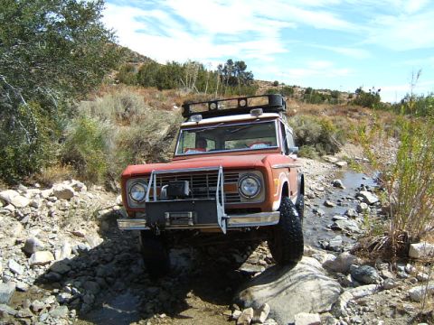1988 Ford Bronco - This vintage Ford Bronco navigates a challenging off-road terrain with a rocky stream bed.
