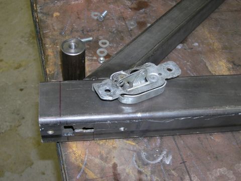 2001 Jeep Wrangler - A metal bracket with a latch mechanism and various hardware components are laid out on a workbench.