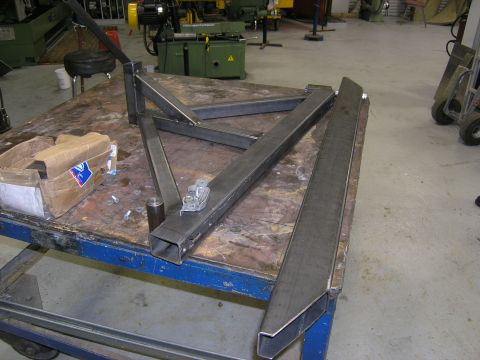 2001 Jeep Wrangler - Unfinished metal bumper components are laid out on a workbench in a workshop setting.