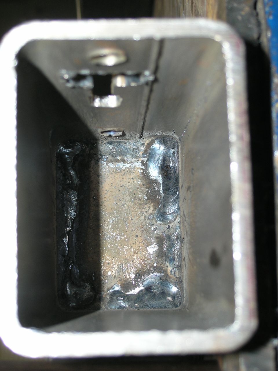 Interior view of a welded metal tube with rough welds visible