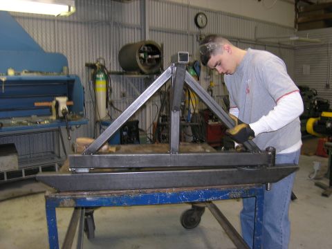 2001 Jeep Wrangler - A person is welding a custom metal frame in a workshop setting.