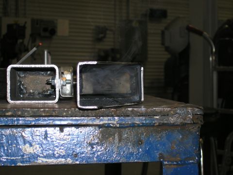 2001 Jeep Wrangler - Two custom metal tubes, likely part of a bumper fabrication, sit on a workbench with smoke rising from one.