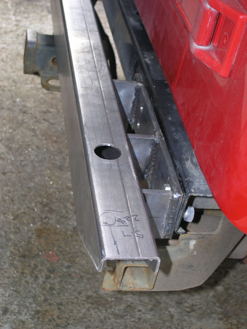 Close-up of a custom metal rear bumper being fabricated, showing welds and a hole for a light