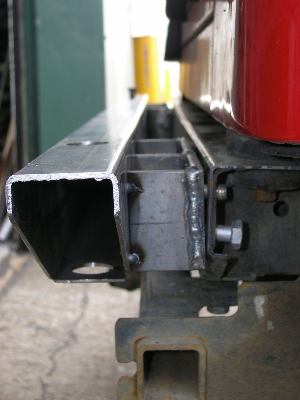 Custom metal bumper bracket with welded supports and bolt mounts, attached to a rusty frame