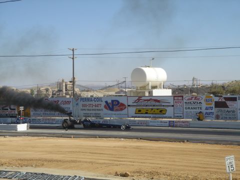 2003 Dodge 3500 - A dragster races down the track, producing a large plume of black smoke.