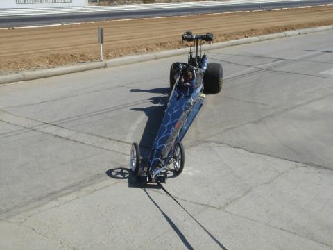2003 Dodge 3500 - A dragster with lightning bolt graphics sits on a paved surface near a raceway.