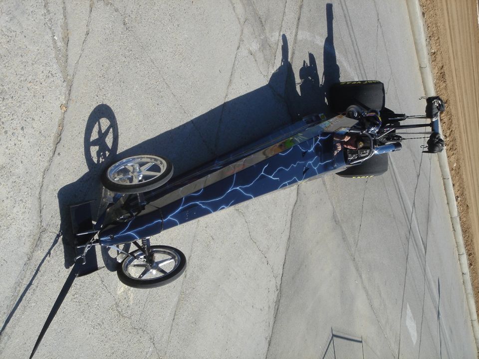 dragster with lightning bolt graphics on its side, sitting on pavement