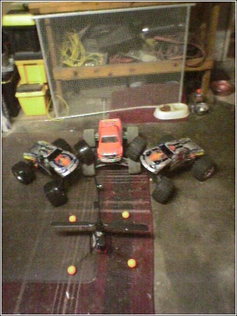 1993 Ford Bronco - Several remote-controlled monster trucks are set up on a floor, possibly for a game or display.