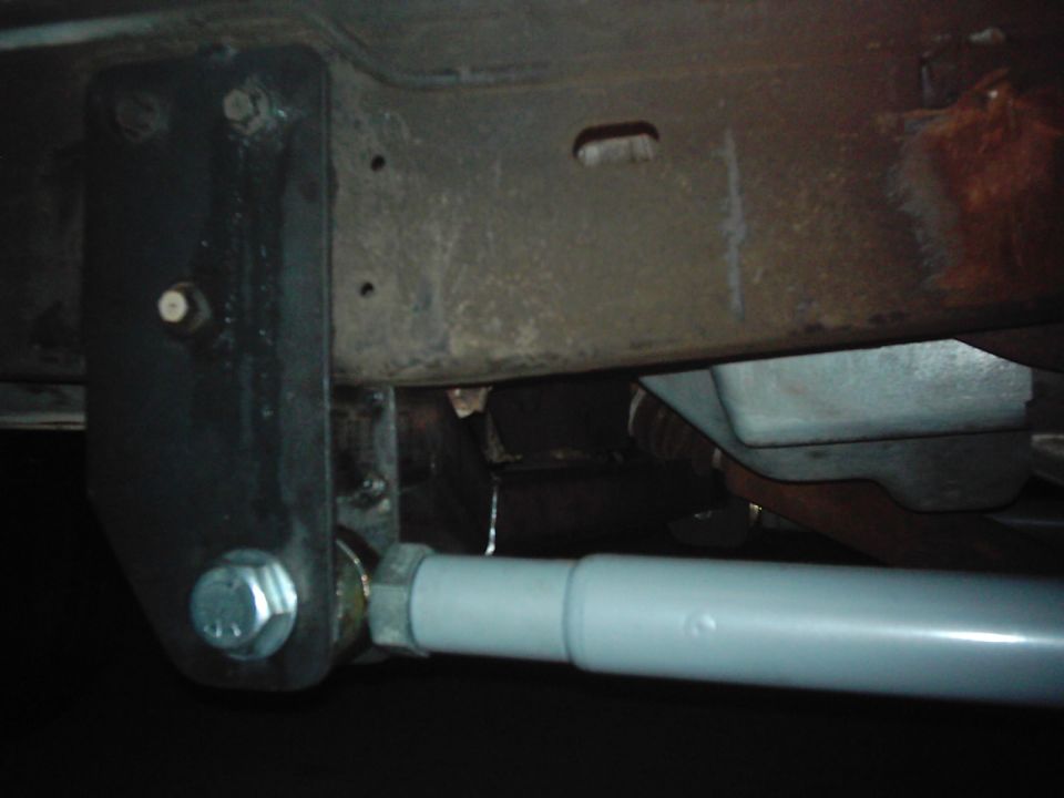 Close-up of a vehicle's rusty frame with a gray shock absorber and black bracket