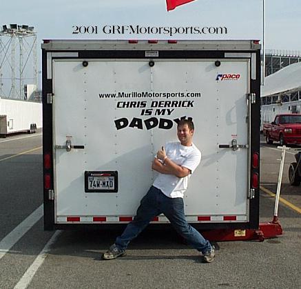 2005 Ford Mustang - A man poses in front of a trailer with text that reads 'CHRIS DERRICK IS MY DADDY', with a red truck visible in the background.