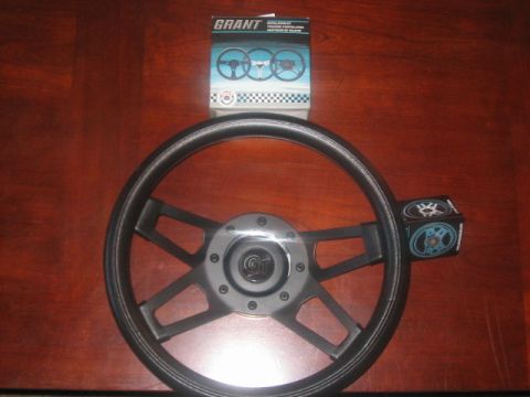 1991 Ford Bronco - Grant steering wheel and its installation kit are displayed on a wooden surface.