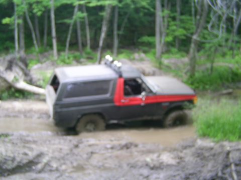 1985 Ford Bronco - This Ford Bronco is navigating a muddy trail in a wooded area.