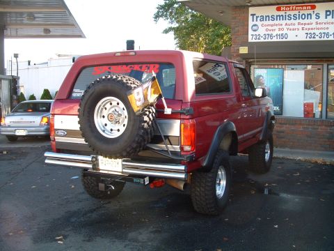 1994 Ford Bronco - Rear view of a red 1994 Ford Bronco with a spare tire and a flag attached.