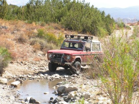 1988 Ford Bronco - First-generation Ford Bronco navigates a rocky, dry stream bed on an off-road trail.