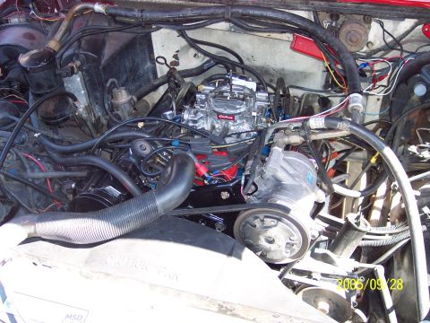 1985 Ford Bronco - Close-up view of a vehicle's engine bay, focusing on the carburetor and associated components.