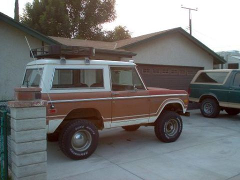 1973 Ford Bronco - A two-tone brown and white 1973 Ford Bronco is parked in a driveway next to another SUV.