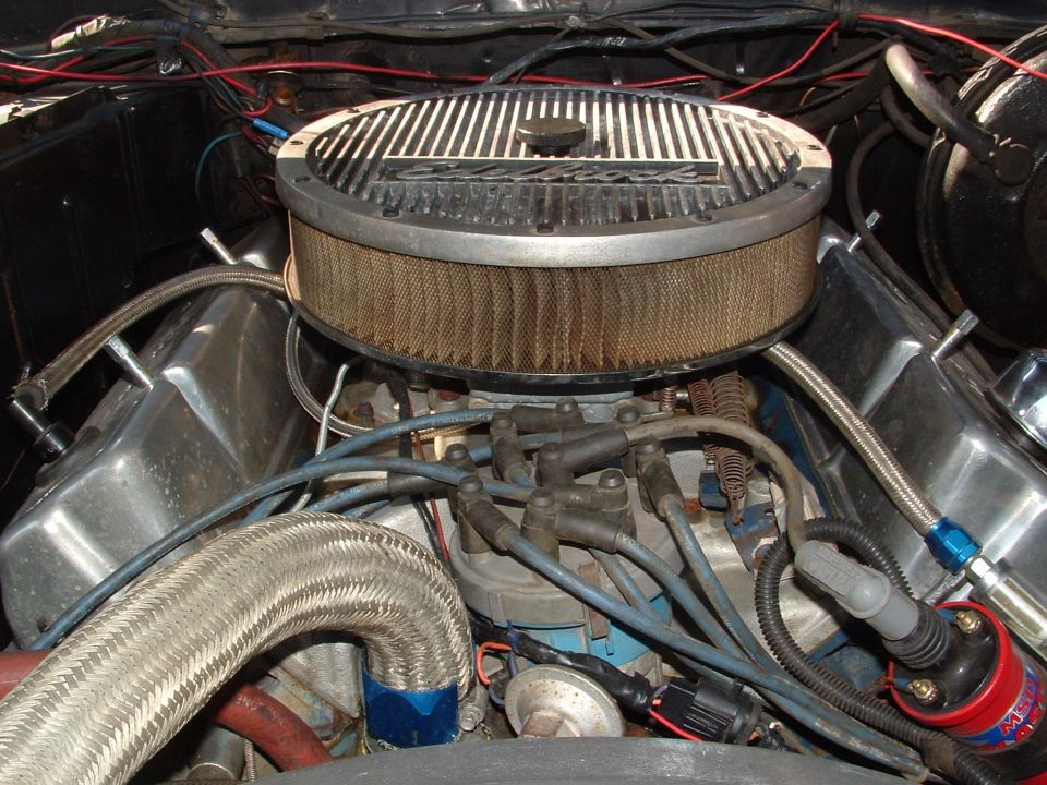Close-up of a V8 engine's air cleaner and valve covers, with spark plug wires visible